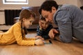 Caring young father with little daughter and son, lying together on floor using digital tablet at home Royalty Free Stock Photo