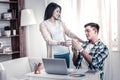 Caring young girlfriend giving cup of tea to her working boyfriend