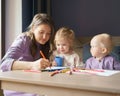 Caring young mom teaching how to draw her two little kids Royalty Free Stock Photo