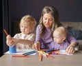 Caring young mom teaching how to draw her two little kids Royalty Free Stock Photo