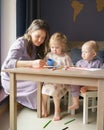 Caring young mom teaching how to draw her two little kids Royalty Free Stock Photo