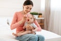 Caring young mother feeding her cute infant baby with mash fruit puree or porridge, giving healthy food to child Royalty Free Stock Photo