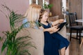 Caring young woman and her little curly daughter reading book together while sitting on armchair Royalty Free Stock Photo