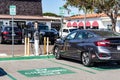 Carlsbad, California - Sept 20, 2021: Electric car plugged into a charging station in a local parking lot with a 2 hour limit sign