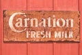 Carnation Milk rusted metal sign on red wooden wall