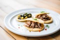 carnitas and black bean stuffed arepas on a white plate