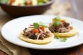 carnitas and black bean stuffed arepas on a white plate