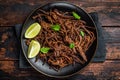 Carnitas in a plate with celery and lime wedges. Wooden background. Top view