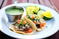 carnitas taco plate with lime wedges and salsa verde