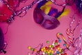 Carnival. Festive background with copy space. Carnival mask on a pink background with tinsel, balloons, multi-colored sweets. Royalty Free Stock Photo