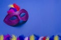 Carnival. Festive background with copy space. Violet carnival mask with feathers on a blue background. Mardi Gras. Brazilian