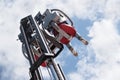 Carnival fun on the fairground, child sits on carousel seats mounted on a forklift and drives upwards into the blue sky with