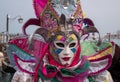 Carnival-goer in traditional costume standing with back to the Grand Canal, with gondolas in background, during Venice Carnival