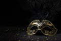 Carnival gold mask with feathers and confetties on black background