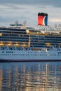 Carnival Luminosa midship with funnel illuminated at dawn reflecting in water