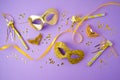 Carnival or mardi gras background with golden carnival masks on violet background. Flat lay composition