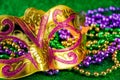 Carnival mask and colorful beads on green shiny background. Mardi Gras concept. Fat Tuesday symbol. Royalty Free Stock Photo