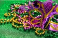 Carnival mask and colorful beads on green shiny background. Mardi Gras concept. Fat Tuesday symbol. Royalty Free Stock Photo