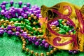 Carnival mask and colorful beads on green shiny background. Mardi Gras concept. Fat Tuesday symbol. Royalty Free Stock Photo