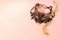 Carnival mask of delicate black lace perfume bottle beads of pearls delicate pink background. Flat layout. Copy space.