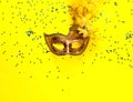 Carnival mask on yellow background with sparkles. Festive backdrop for projects. Flat lay, close up. Royalty Free Stock Photo