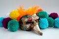 Carnival mask with yellow feathers and colorful wool pom poms isolated on the white background