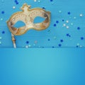 carnival party celebration concept with elegant gold mask on stick over blue wooden background and stars. Top view. Royalty Free Stock Photo