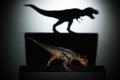 A carnotaurus casting a tyrannosaurus shadow in dark concept of strength & aspirations