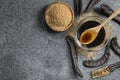 Carob molasses in glass bowl and carob powder or flour with carob pods on rustic background