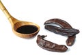 Carob pods and carob syrup in wooden spoon on the white background