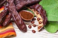 Carob with powder. Organic carob pods with seeds and leaves on white wooden table. Healthy eating, food background