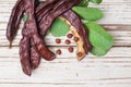 Carob top view. Organic carob pods with seeds and leaves on white wooden table. Healthy eating, food background Royalty Free Stock Photo