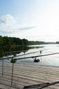 Carp fishing on beautiful blue lake with carp rods and rod pods in the summer morning. Fishing from the wooden platform Royalty Free Stock Photo