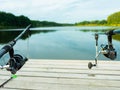 Carp fishing on beautiful blue lake with carp rods and rod pods in the summer morning. Fishing from the wooden platform Royalty Free Stock Photo