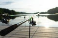 Carp fishing on beautiful blue lake with carp rods and rod pods in the summer morning. Fishing from the wooden platform Royalty Free Stock Photo