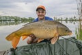 Carp fishing. Fisherman with fish trophy in hands at lake