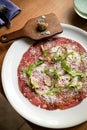 Carpaccio with parmesan, truffles and arugula on a white plate