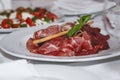 Carpaccio on a plate on a festive table with a white tablecloth. Appetizing cold appetizers. Close-up