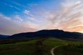 Carpathian meadow and beautiful sunset in the mountains - spring landscape, spruces on the hills, dark cloudy sky and bright Royalty Free Stock Photo