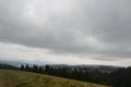 Carpathian mountains with green slopes under low in thick clouds on a cloudy day Royalty Free Stock Photo