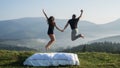 Carpathians, Ukraine - September 13, 2019: Man and woman jumping on the mountain at dawn. Loving couple resting in the mountains