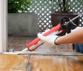 Carpenter applies silicone caulk on the wooden floor for sealing