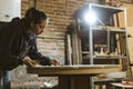 Carpenter / Artisan girl is concentrated working on an old wood table in her workshop. Woman restores an antique furniture Royalty Free Stock Photo