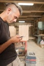 Carpenter artisan resting in workshop and scrolling on smartphone