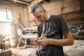 Carpenter artisan resting in workshop and scrolling on smartphone