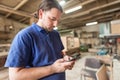 Carpenter artisan resting in workshop and scrolling on smartphone