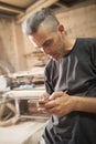 Carpenter artisan resting in workshop and scrolling on smartphone