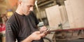 Carpenter artisan resting in workshop and scrolling on smartphone