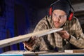 carpenter blowing sawdust from wooden plank after cutting with circular saw Royalty Free Stock Photo