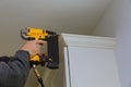 Carpenter brad using nail gun to Crown Moulding on kitchen cabinets Royalty Free Stock Photo